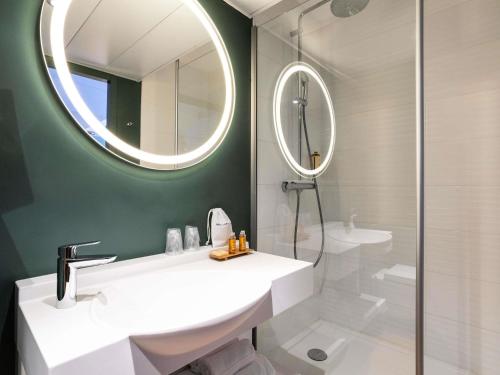 a bathroom with a white sink and a mirror at Mercure Saint Omer Centre Gare in Saint-Omer