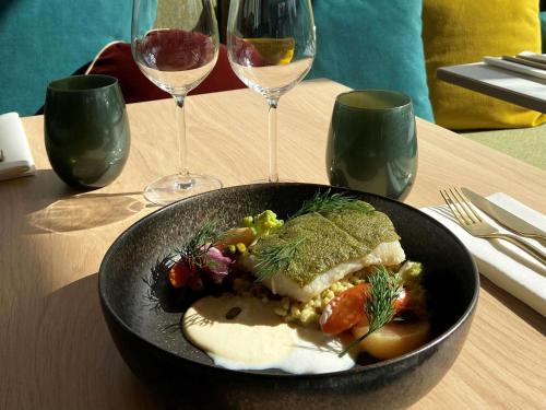 a black bowl of food on a table with wine glasses at Mercure Saint Omer Centre Gare in Saint-Omer