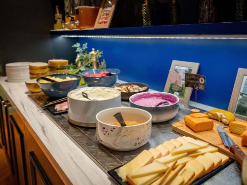 a buffet with cheese and other foods on a counter at Mercure Saint Omer Centre Gare in Saint-Omer