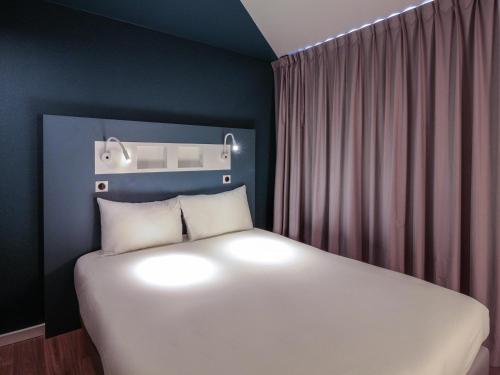 a bedroom with a large white bed in a room at ibis budget Rouen Centre Rive Gauche in Rouen