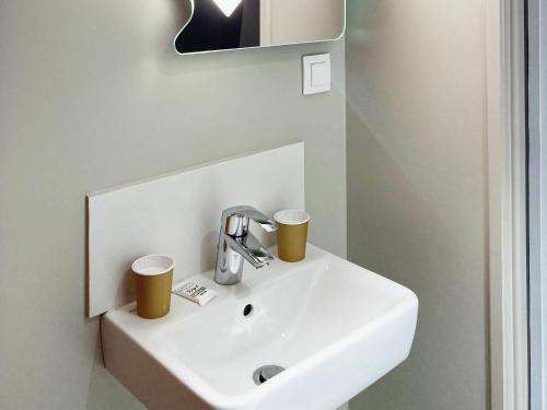 a bathroom sink with two cups on it at ibis budget Rouen Centre Rive Gauche in Rouen