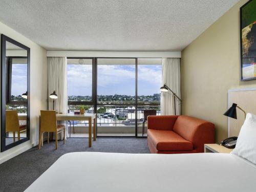 a hotel room with a bed and a desk and chair at Mercure Rockhampton in Rockhampton