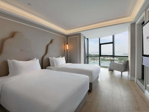 a hotel room with two beds and a large window at Mercure Xiamen Zhongshan Road Pedestrian Street Seaview in Xiamen