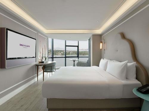 a bedroom with a large white bed and a desk at Mercure Xiamen Zhongshan Road Pedestrian Street Seaview in Xiamen