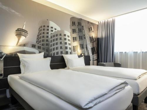 two beds in a hotel room with buildings on the wall at Novotel Duesseldorf Airport in Düsseldorf