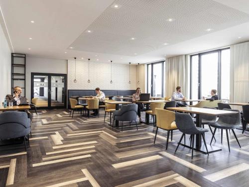 a restaurant with people sitting at tables and chairs at Novotel Duesseldorf Airport in Düsseldorf