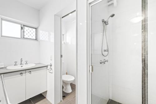 a white bathroom with a shower and a toilet at Maroochy Sands Holiday Apartments in Maroochydore