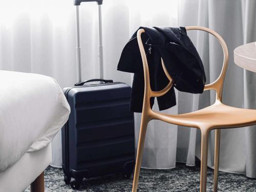 a bedroom with a chair and a suitcase at ibis Styles Nancy Laxou in Nancy