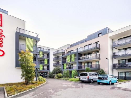an apartment building with cars parked in a parking lot at Aparthotel Adagio Bâle Mulhouse Aeroport in Blotzheim