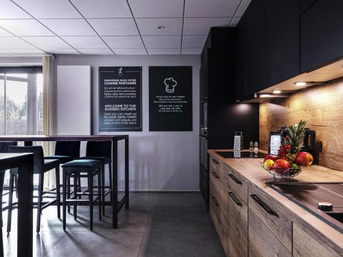 a kitchen with a counter with stools and a bar at Aparthotel Adagio Bâle Mulhouse Aeroport in Blotzheim