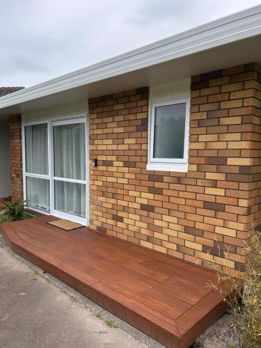 a brick house with a wooden deck in front of it at Coastal Comfort in Mount Maunganui