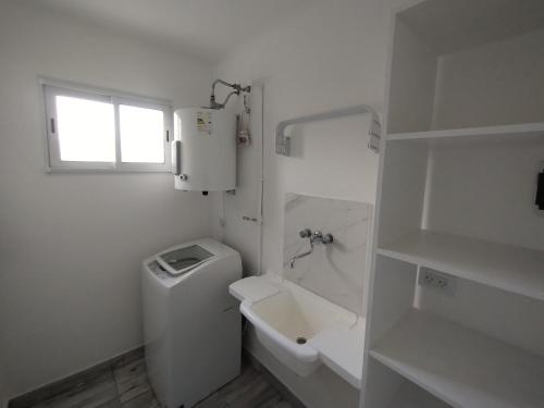 a white bathroom with a toilet and a sink at Casa con Jardín Las Marías 2 in Miramar