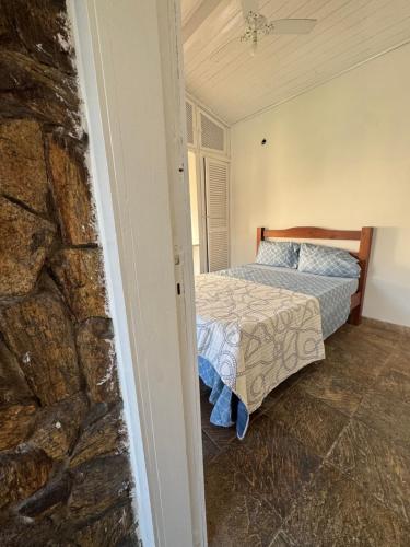 une chambre avec un lit et un mur en pierre dans l'établissement Aconchego da praia, à Arraial do Cabo