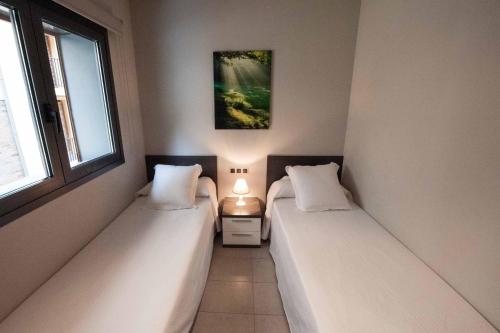 two beds in a room with two windows at WinTuWin Apartments in Rialp