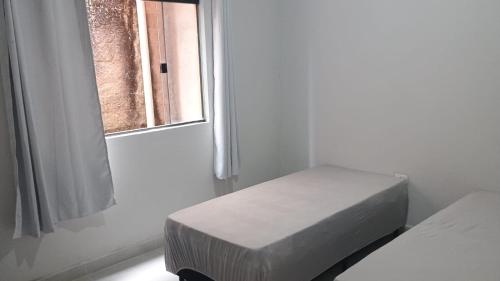 una stanza bianca con un letto e una finestra di J&M Ubatuba a Ubatuba