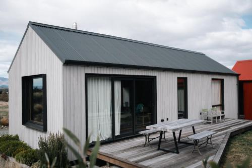 OhauにあるBackcountry hut with a modern twistの木製デッキ付きの小さな白い建物