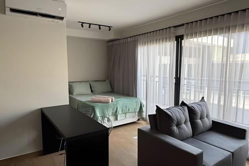 a living room with a couch and a bed and a window at Max Jardim São Paulo in São Paulo