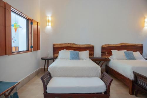 a bedroom with two beds and a window at Hotel Posada San Juan in Valladolid