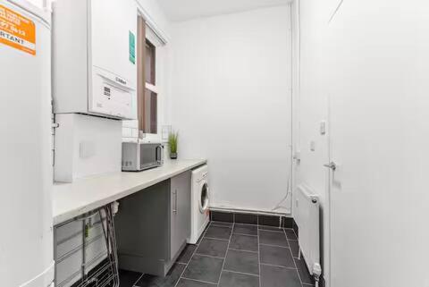 a kitchen with white counters and a washer and dryer at 4-Bedroom House with Parking Contractors & Long Stays in Sheffield
