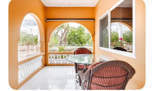 a balcony with a glass table and two windows at Brytan Villa in Treasure Beach