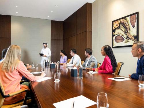 a group of people sitting around a table in a conference room at Swissôtel Al Ghurair Dubai - Deira & Creek in Dubai