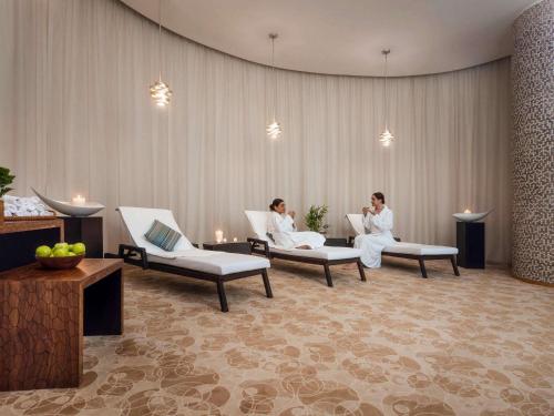two people sitting on chairs in a room at Swissôtel Al Ghurair Dubai - Deira & Creek in Dubai