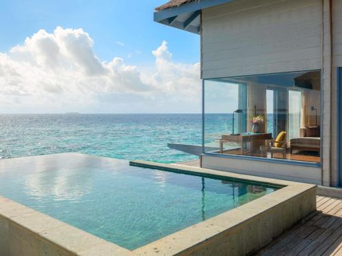 a house with a swimming pool next to the ocean at Raffles Maldives Meradhoo in Gaafu Alifu Atoll