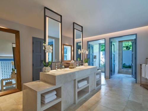 a bathroom with two sinks and two mirrors at Raffles Maldives Meradhoo in Gaafu Alifu Atoll