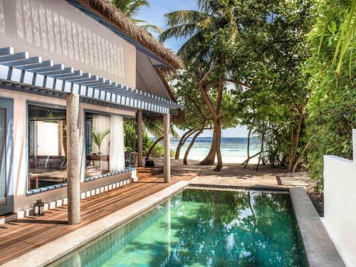 a villa with a swimming pool in front of the ocean at Raffles Maldives Meradhoo in Gaafu Alifu Atoll
