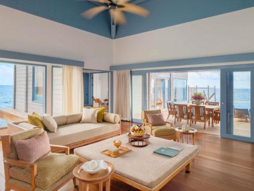 a living room with a couch and a table at Raffles Maldives Meradhoo in Gaafu Alifu Atoll