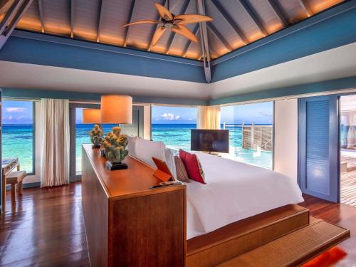 a bedroom with a bed and a view of the ocean at Raffles Maldives Meradhoo in Gaafu Alifu Atoll