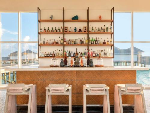a bar with two chairs and a counter with bottles at Raffles Maldives Meradhoo in Gaafu Alifu Atoll