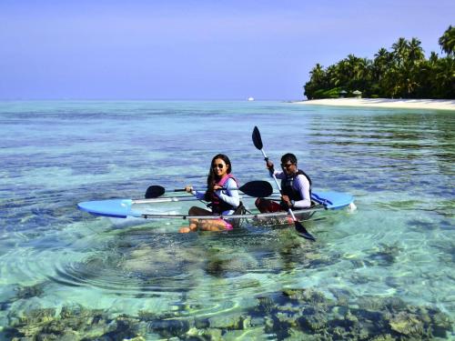 a man and a woman sitting on a kayak in the water at Raffles Maldives Meradhoo in Gaafu Alifu Atoll