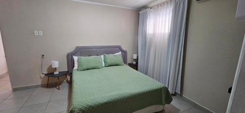 a bedroom with a bed with a green blanket and a window at Taminaka Apartamento Comfortable III in Paradijs
