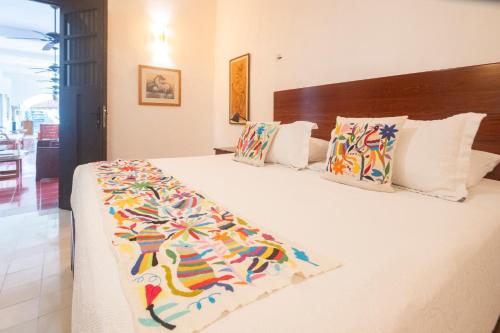 a bedroom with a large white bed with colorful pillows at Hotel Posada San Juan in Valladolid