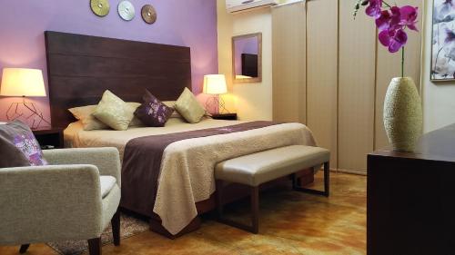 a hotel room with a bed and a chair and purple walls at Hotel Boutique La Casona in Axtla