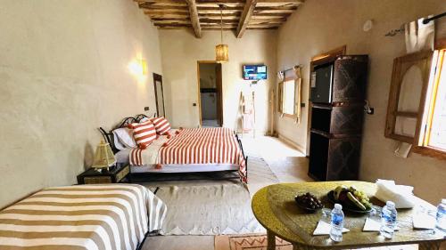 a room with two beds and a table in it at Nana Diafa - Luxury Stay in Zagora in Zagora