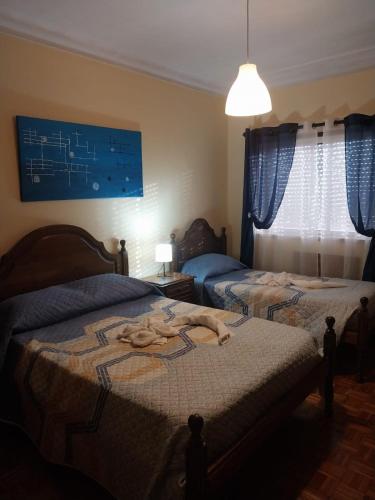 two beds in a bedroom with blue curtains at Seia Flat Mountain Seia View in Seia