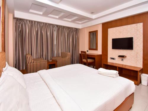 a hotel room with a bed and a desk and a television at The Vijay Park, Madhavaram in Chennai