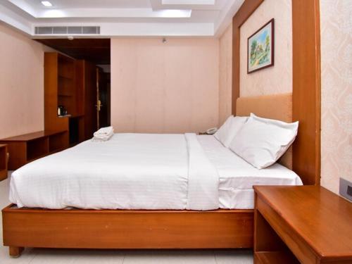 a bedroom with a large bed with white sheets at The Vijay Park, Madhavaram in Chennai