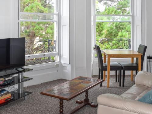 Una sala de estar con una mesa y dos ventanas. en Solent Charm, en Ryde
