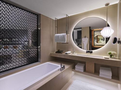 a bathroom with a tub and a large mirror at Fairmont Riyadh in Riyadh