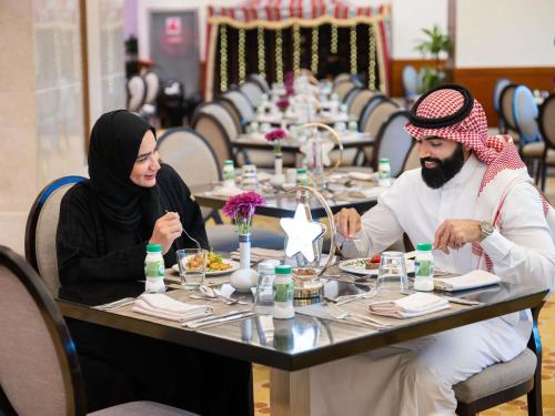 a man and a woman sitting at a table at Swissotel Al Maqam Makkah in Makkah