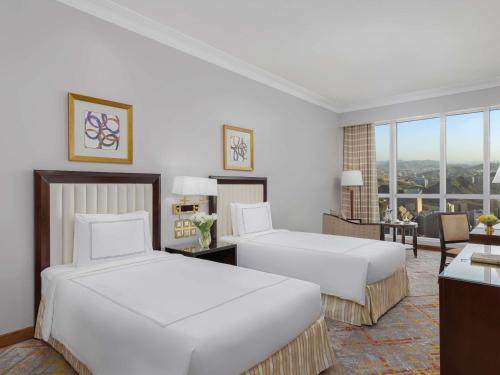 a hotel room with two beds and a living room at Swissotel Al Maqam Makkah in Makkah