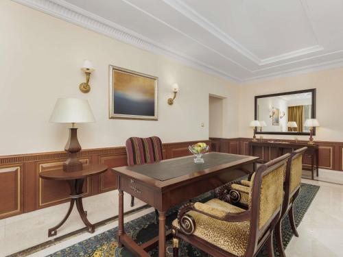 a room with a desk and a table and chairs at Swissotel Al Maqam Makkah in Makkah