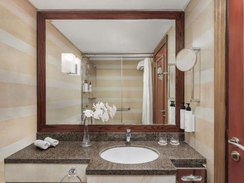 a bathroom with a sink and a large mirror at Swissotel Al Maqam Makkah in Makkah