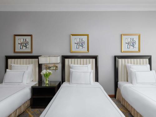 two beds in a room with white walls at Swissotel Al Maqam Makkah in Makkah