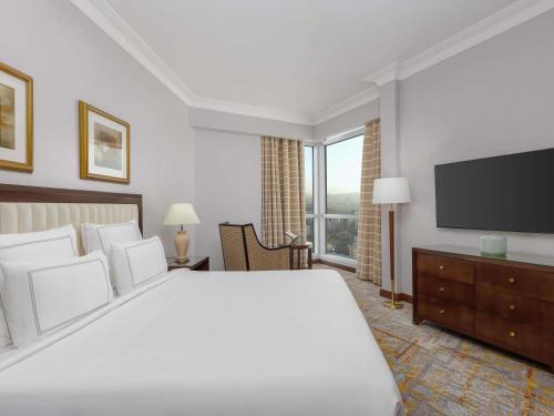 a bedroom with a large bed and a flat screen tv at Swissotel Al Maqam Makkah in Makkah