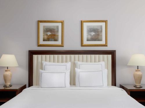 a bedroom with a large white bed with two lamps at Swissotel Al Maqam Makkah in Makkah