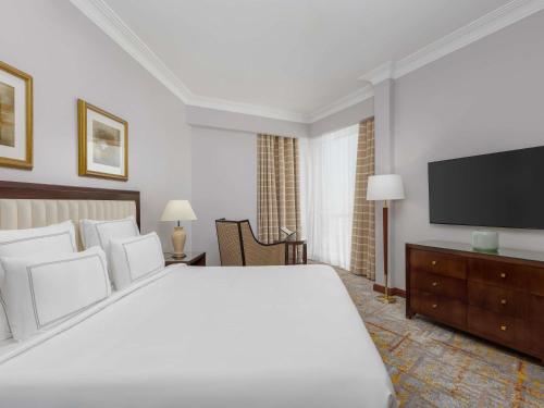 a bedroom with a large bed and a flat screen tv at Swissotel Al Maqam Makkah in Makkah